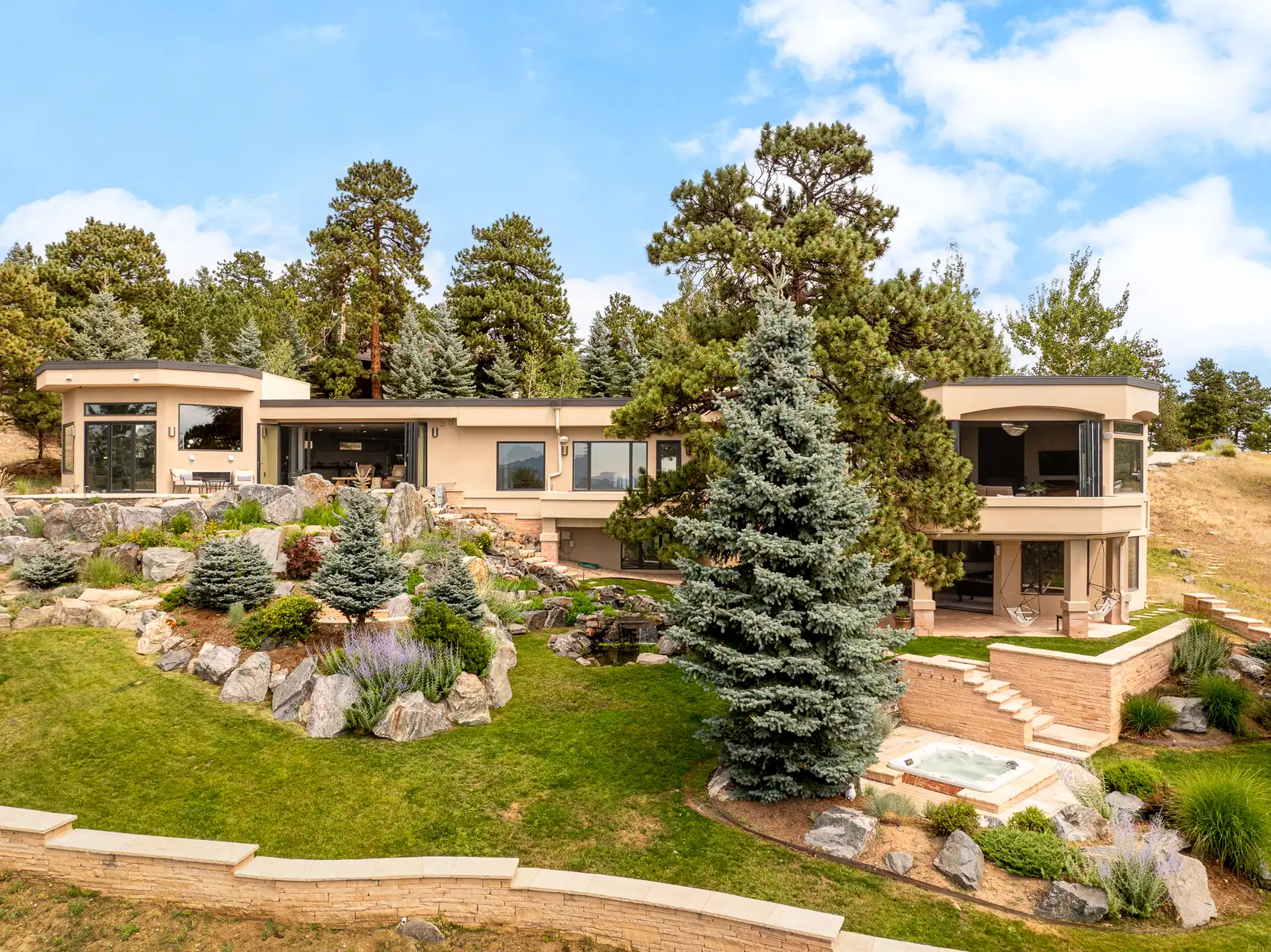 Elevated view of the rear terraces, rock garden and hot tub in summer.