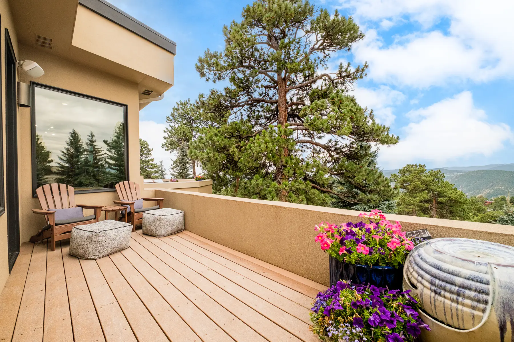 Private deck off the primary bedroom with chairs, planters and a ponderosa beyond.