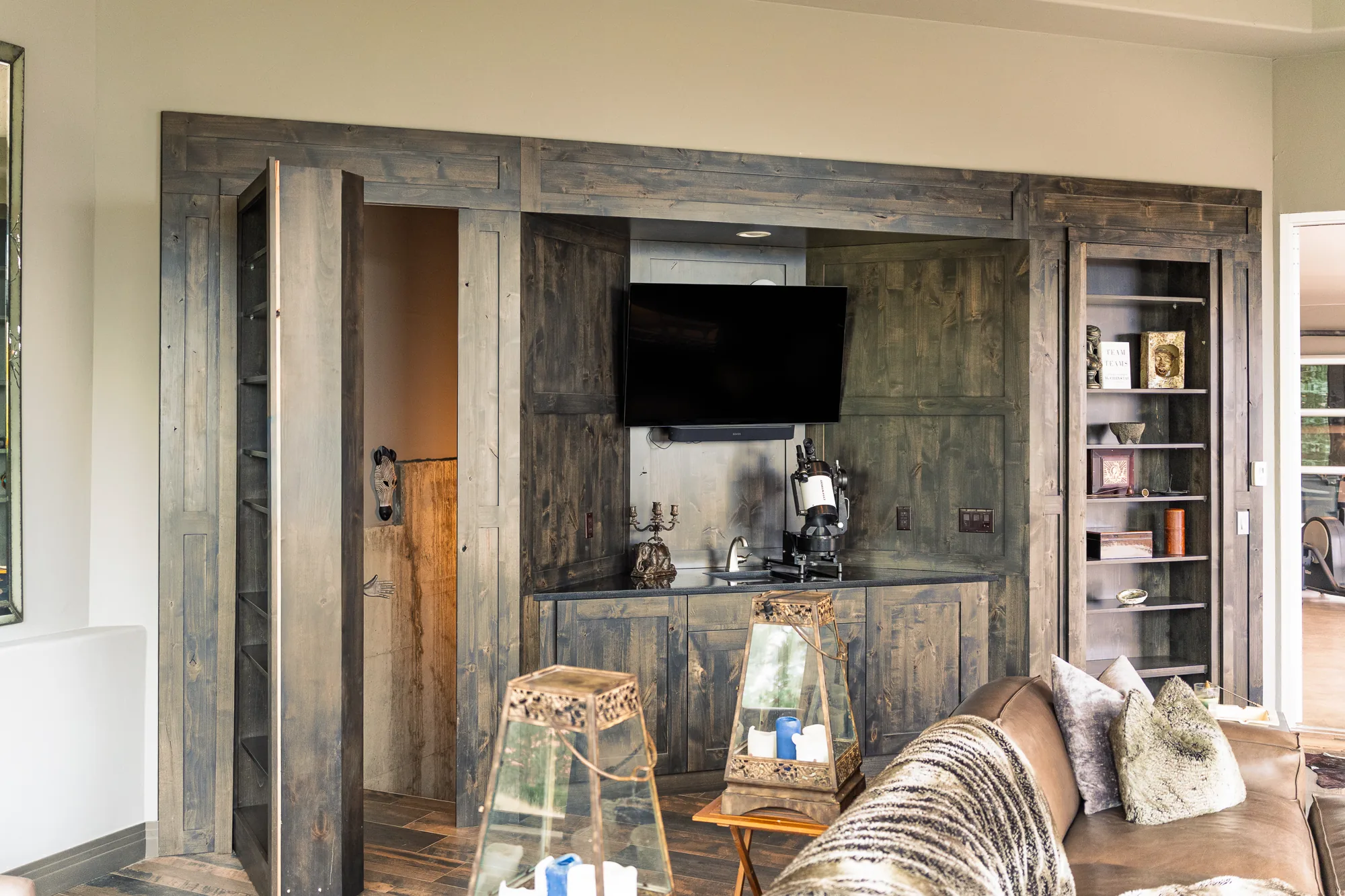 Weathered barnwood media wall with built-in shelving, wet bar and concealed doors.
