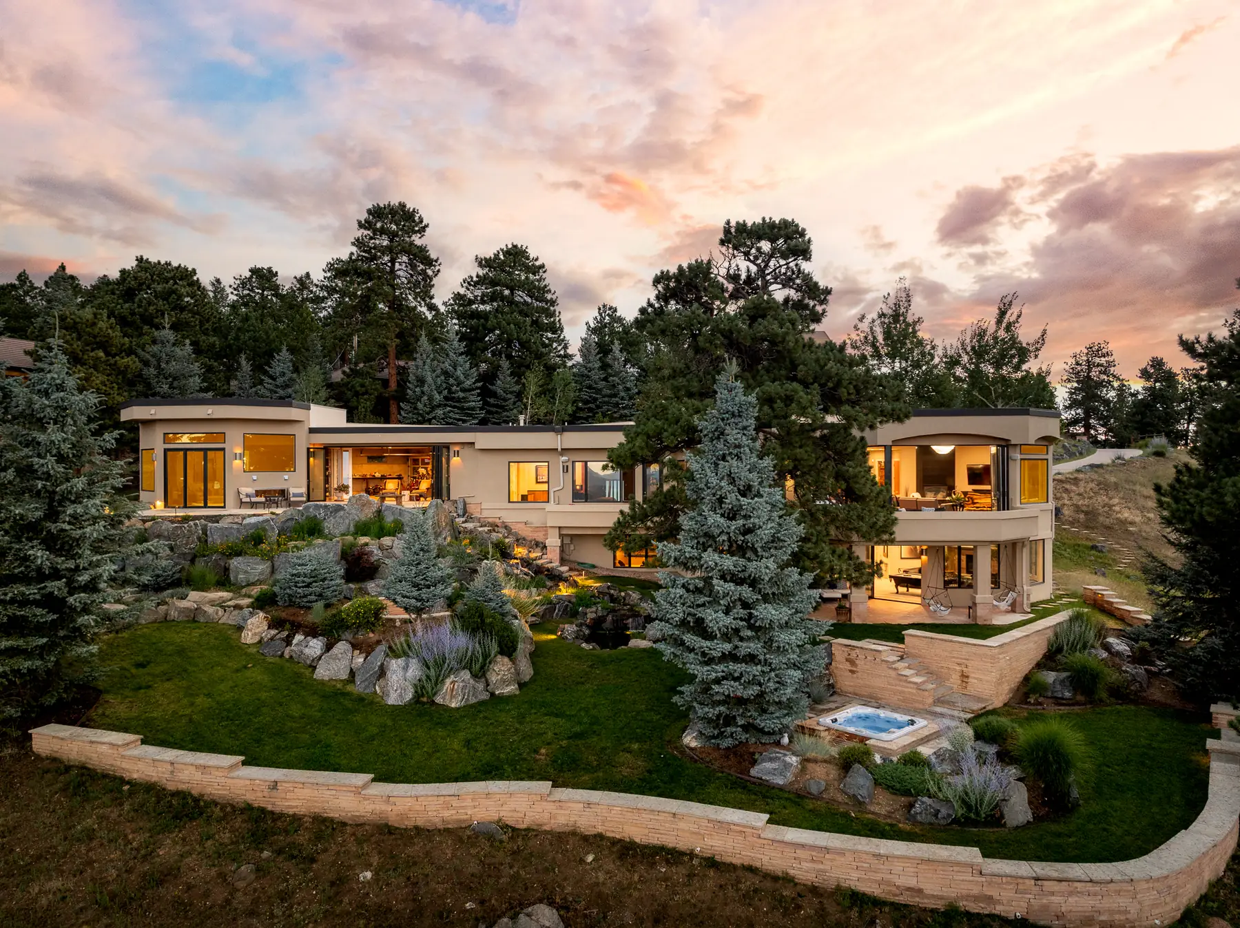 Aerial rear view of a custom home at dusk, set into the Colorado foothills