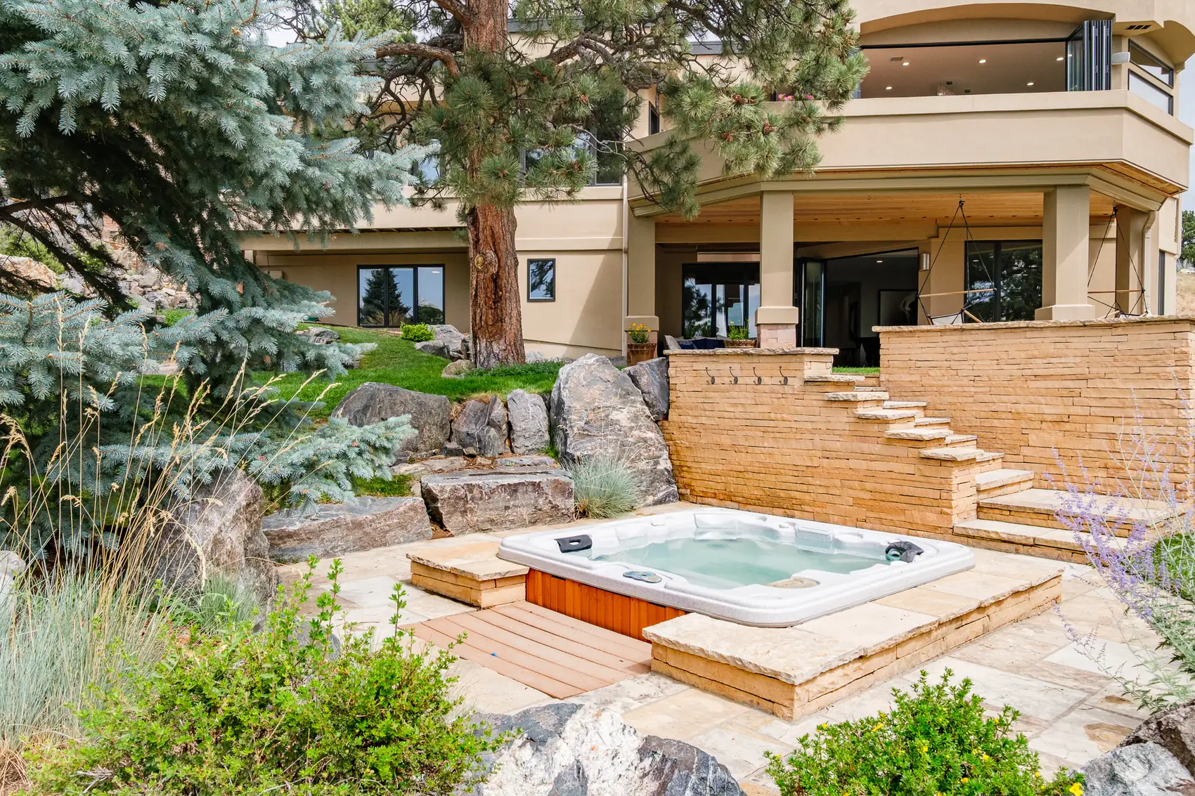 Hot tub set into a flagstone terrace beneath the covered lower level.