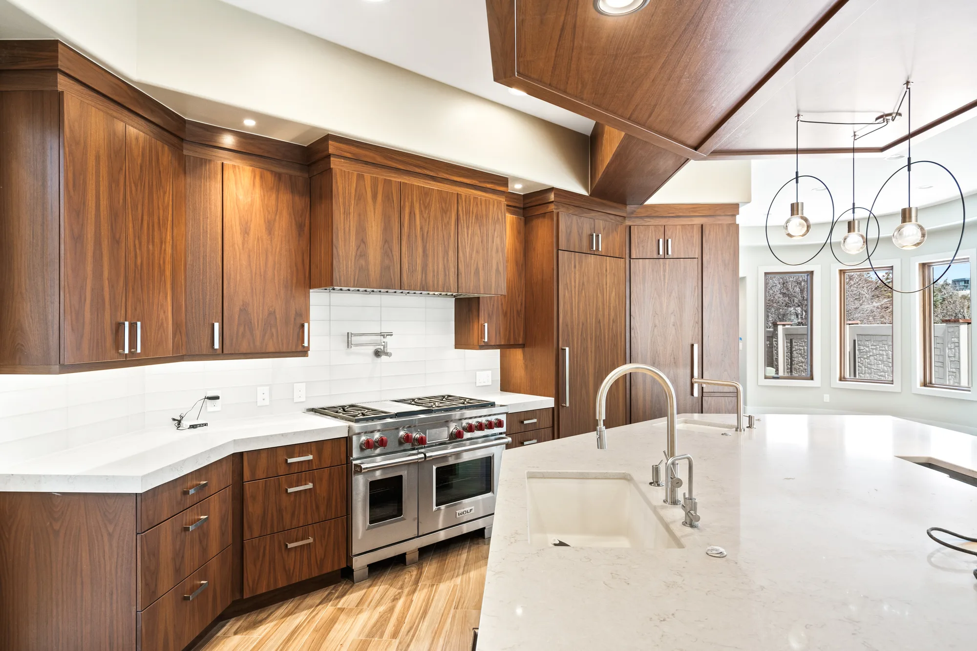 Kitchen with book-matched walnut cabinetry, a faceted walnut ceiling canopy, quartz island, and a professional range