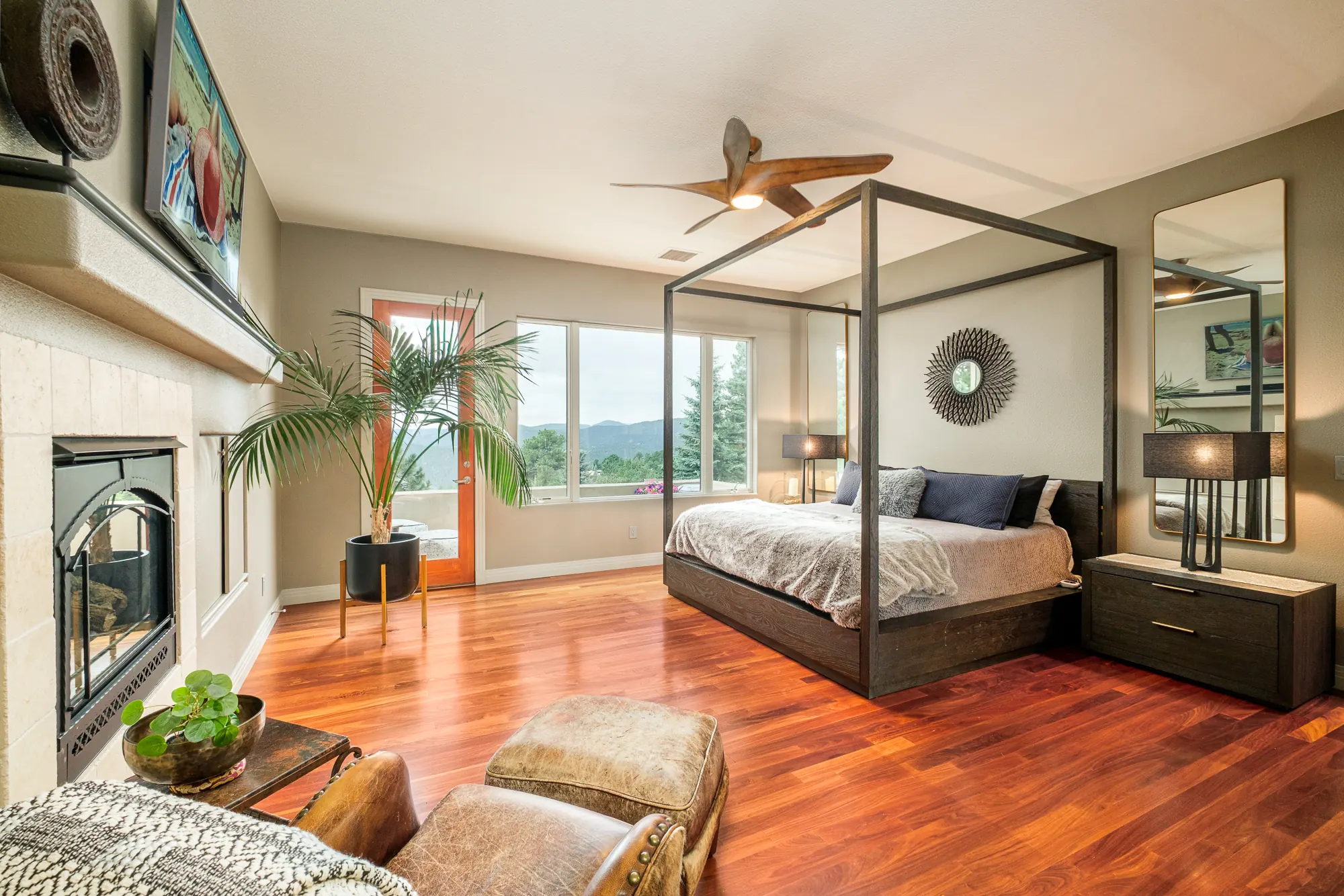 Primary bedroom with a canopy bed, corner fireplace and windows onto the ridge.