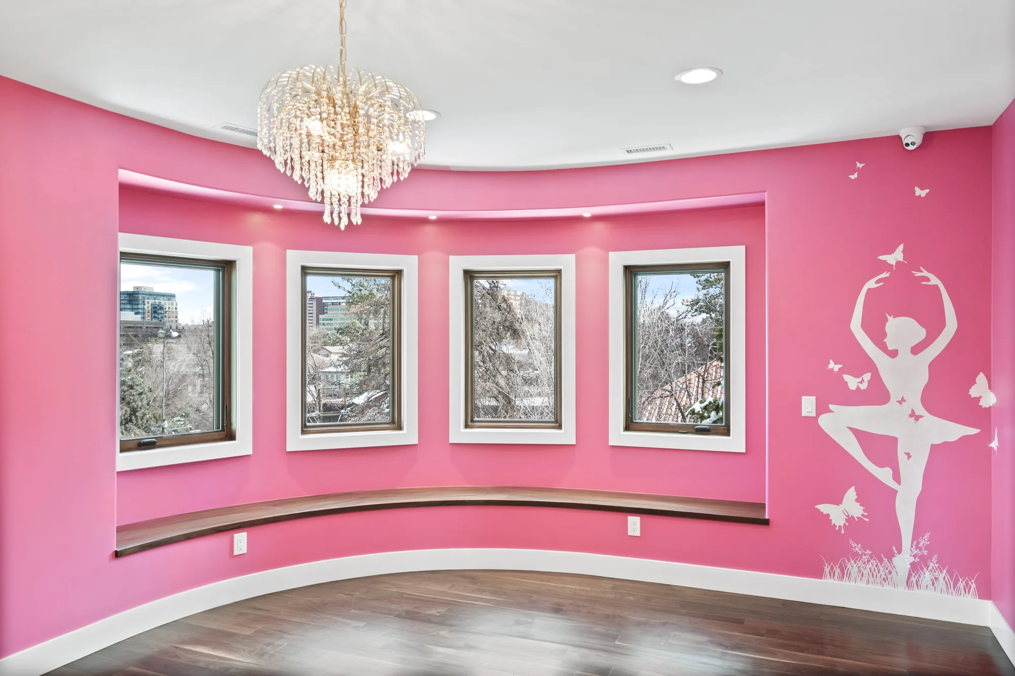 Curved turret room with a built-in walnut window seat following the radius, four windows, and a crystal chandelier
