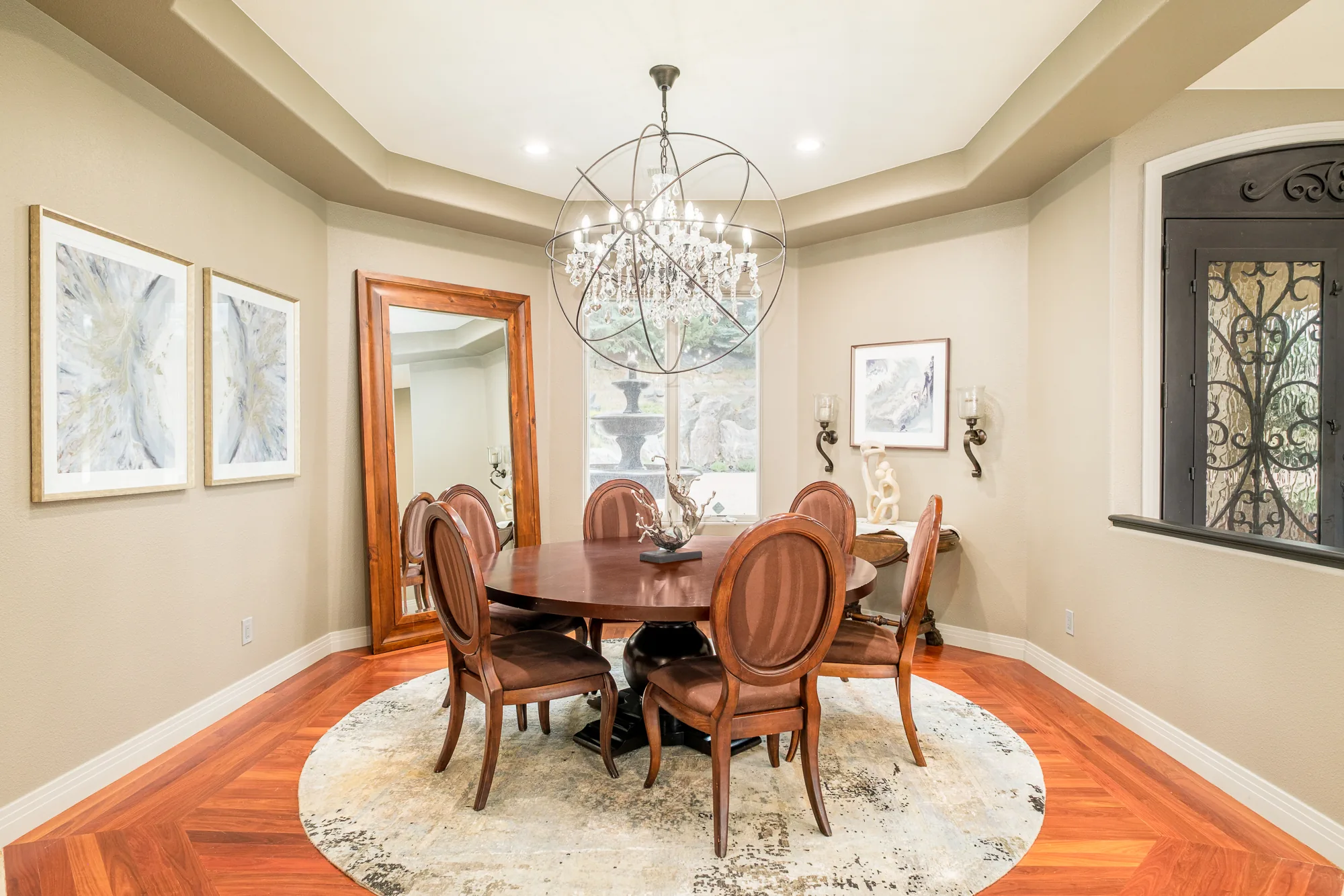 Round dining table centered beneath a chandelier in a symmetrical dining room.