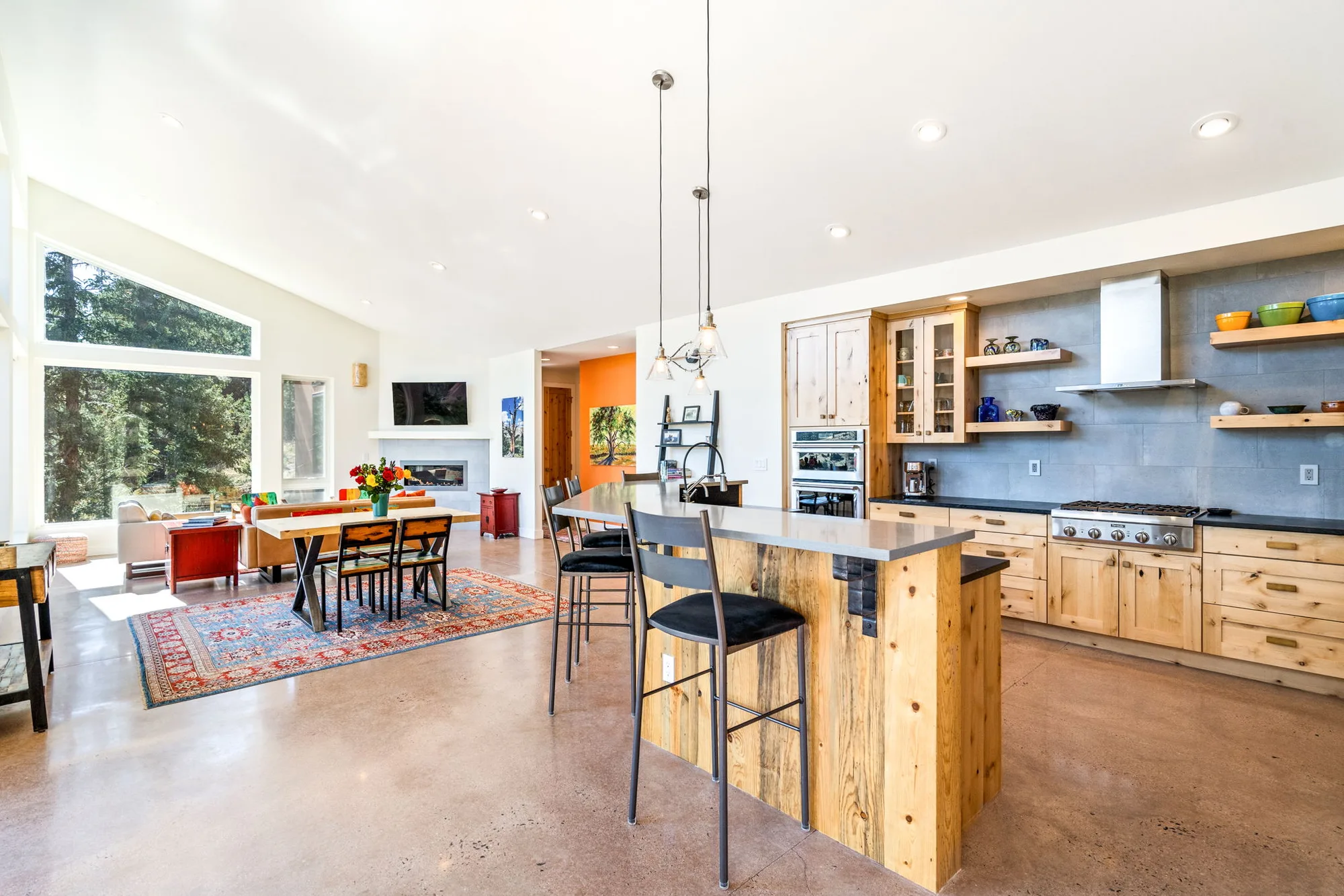 Kitchen island with a reclaimed timber base opening directly onto the dining and living areas under the sloped ceiling