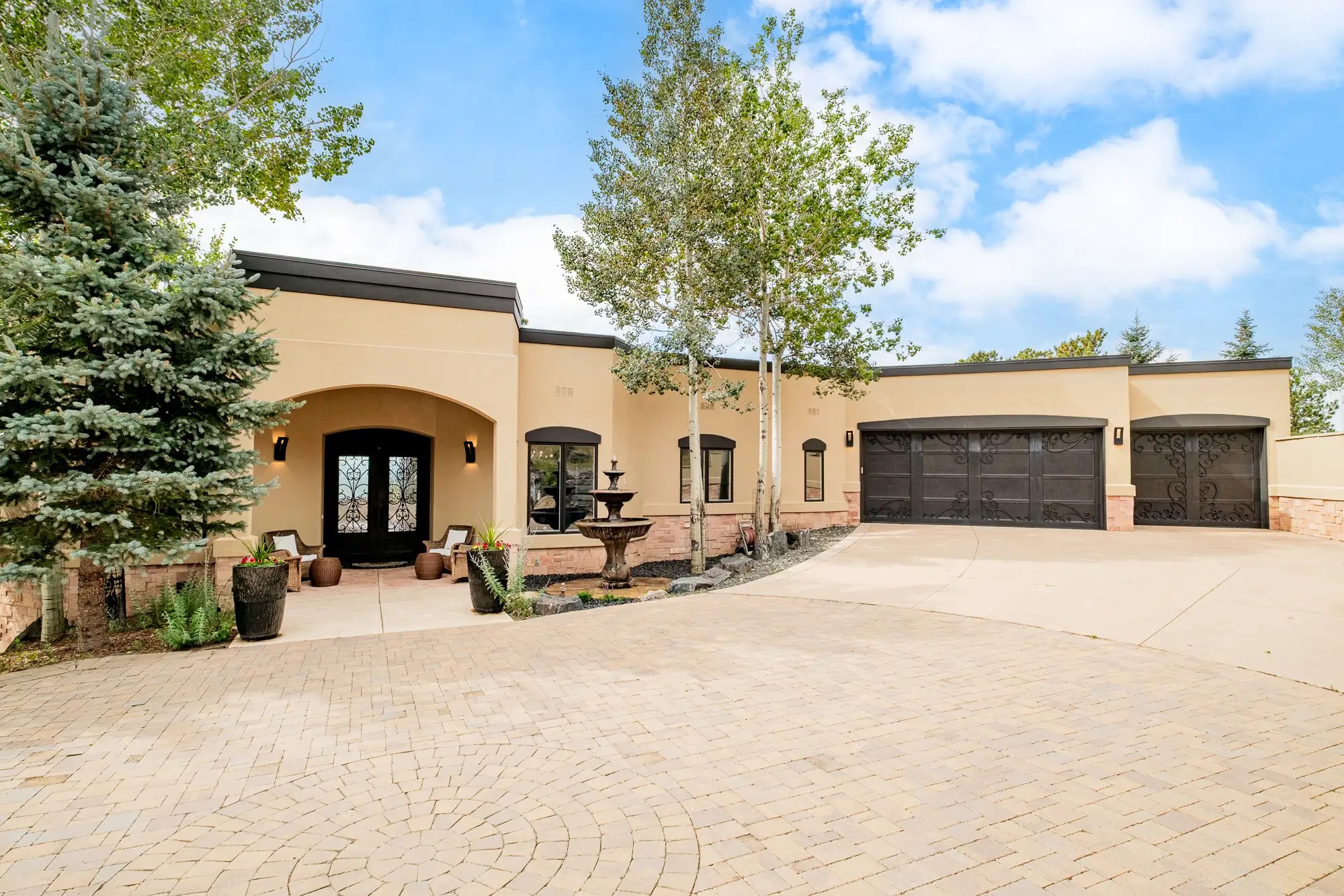 Front elevation in daylight with the arched entry, fountain and paver court.