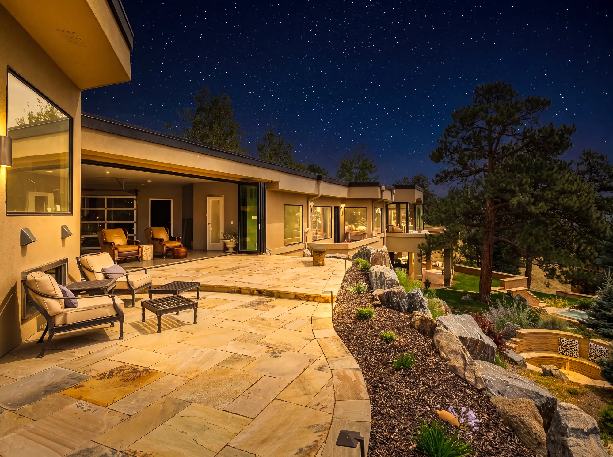 Flagstone patio under a clear night sky with the house lit along its length.