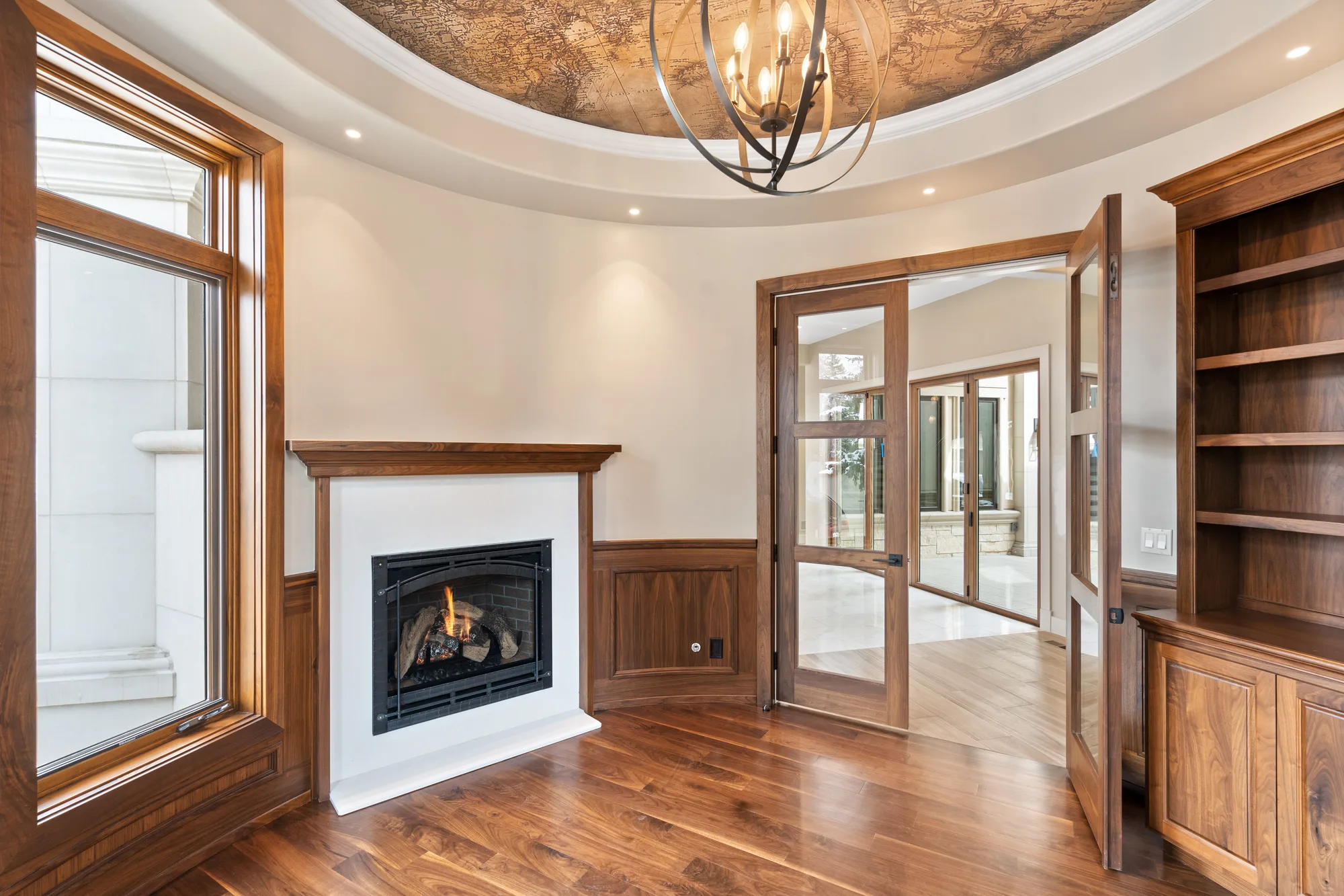 Office in raised-panel walnut wainscot with built-in bookcases, a fireplace, and a domed ceiling papered in an antique world map