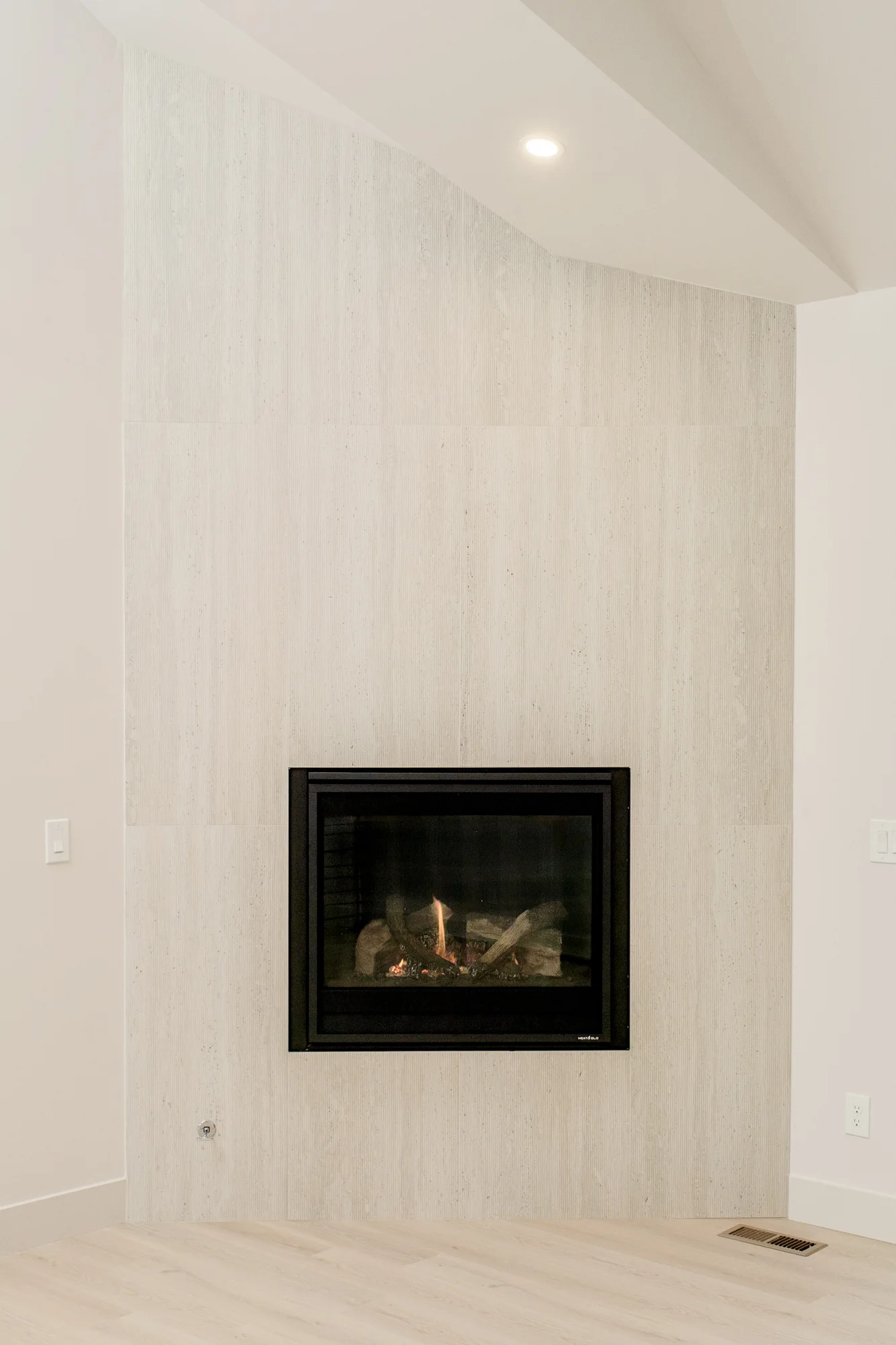 Travertine fireplace wall carried floor to vault with a black steel firebox at its center
