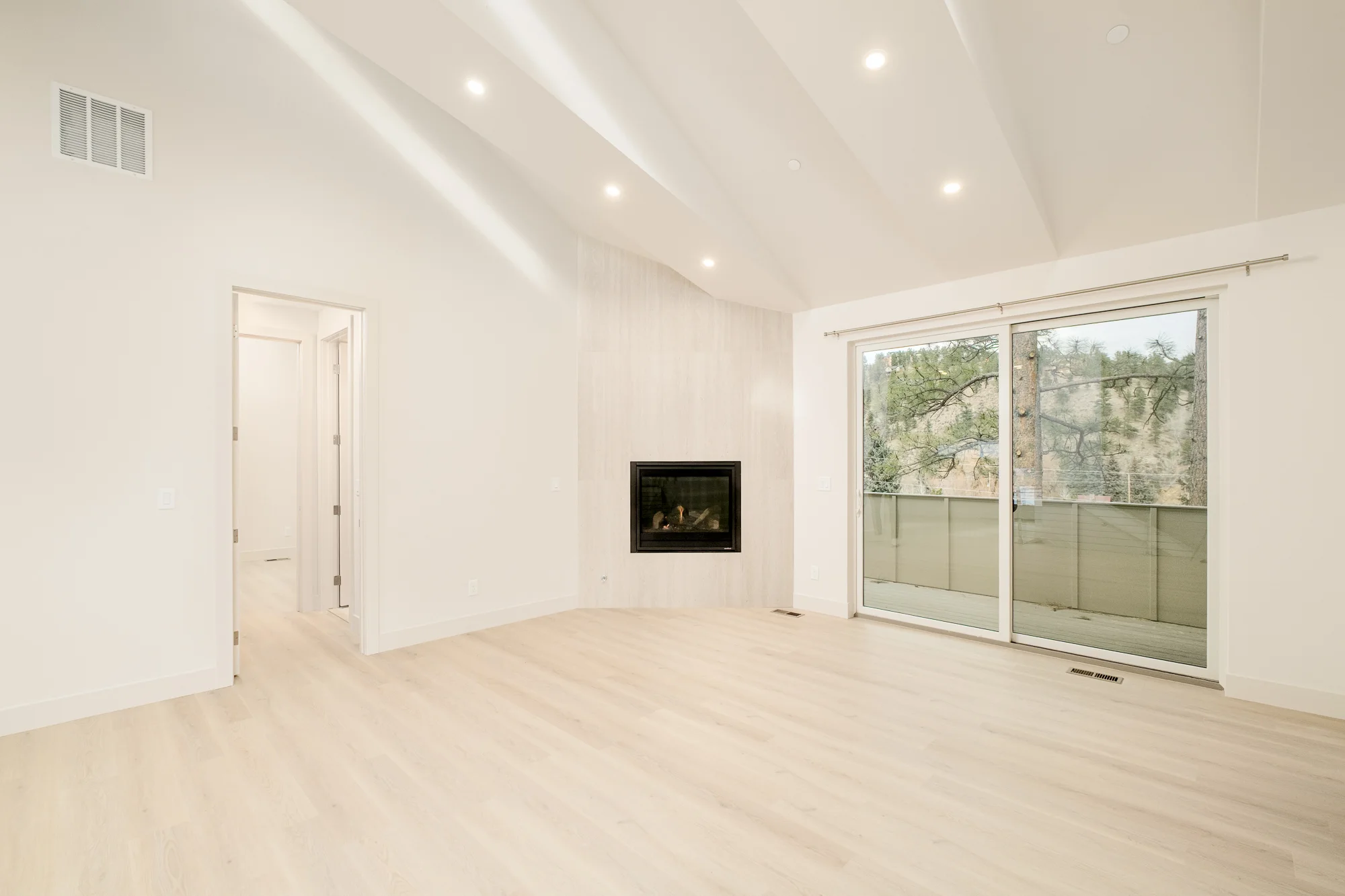 Living room with the deck slider open to the pines and canyon wall beyond