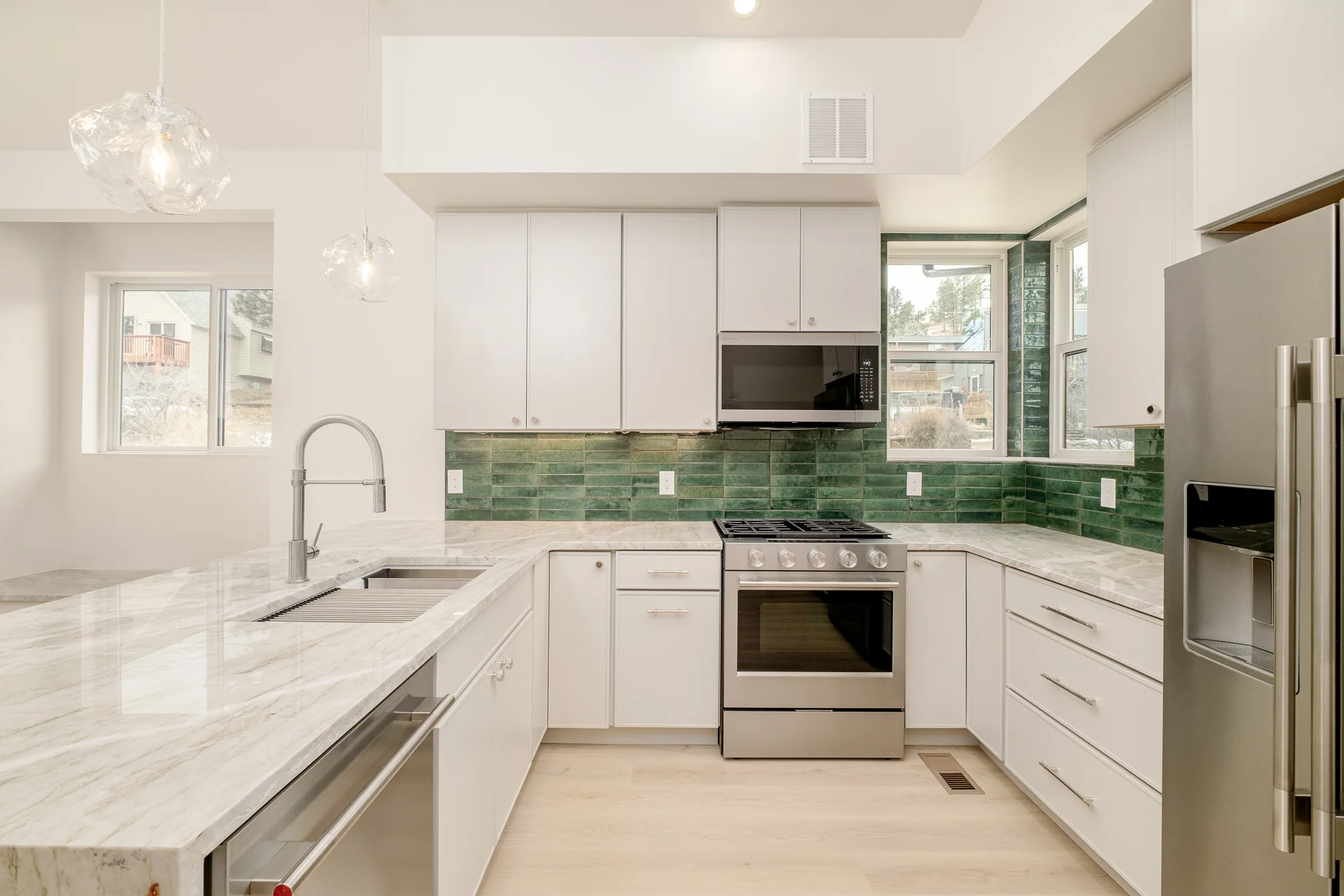 Kitchen range wall in green glazed tile, with stainless appliances and quartzite counters
