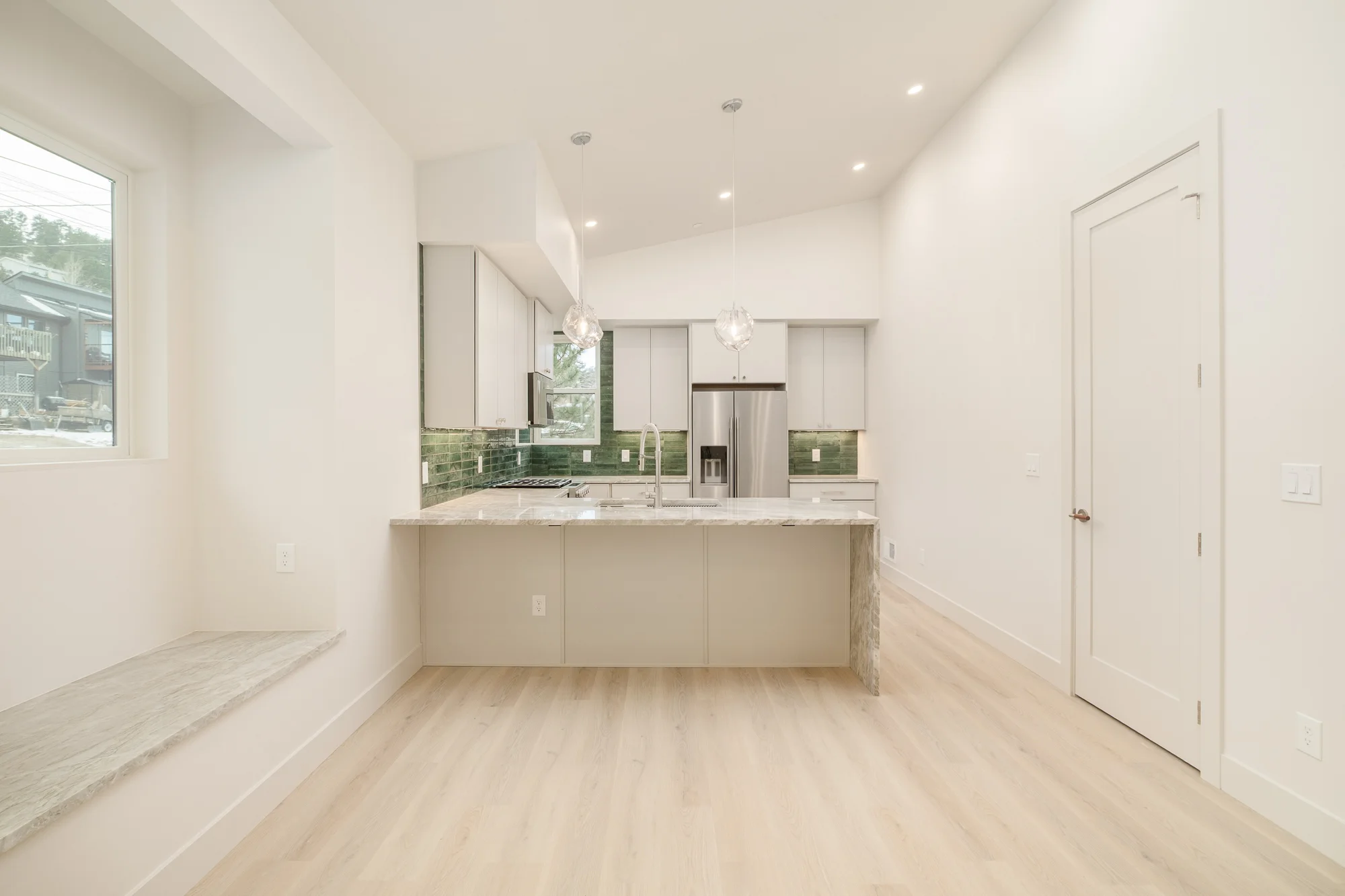 Kitchen peninsula seen from the dining side, with a quartzite window seat at the left