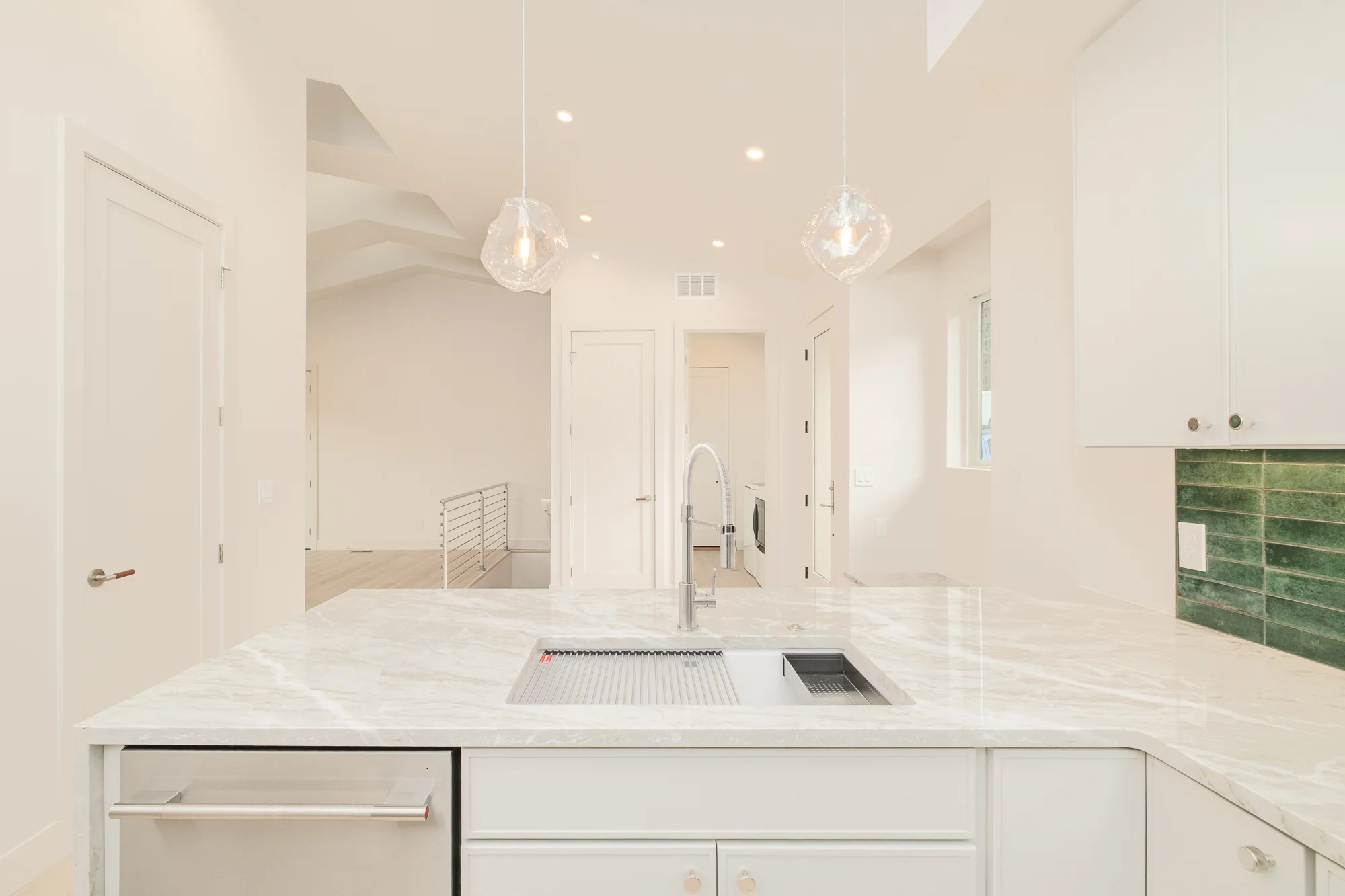 Island sink with a workstation basin, pull-down faucet and two hand-blown glass pendants above