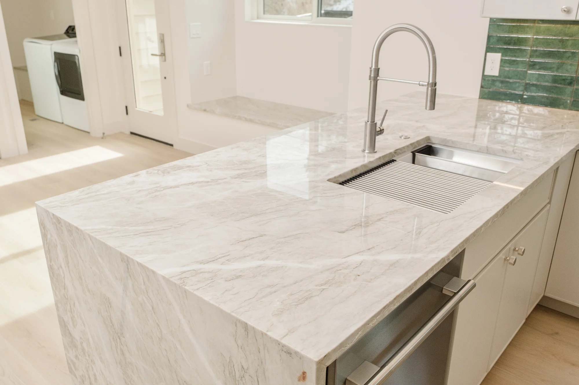 Close view of the quartzite island, its mitered waterfall edge and integrated drain board