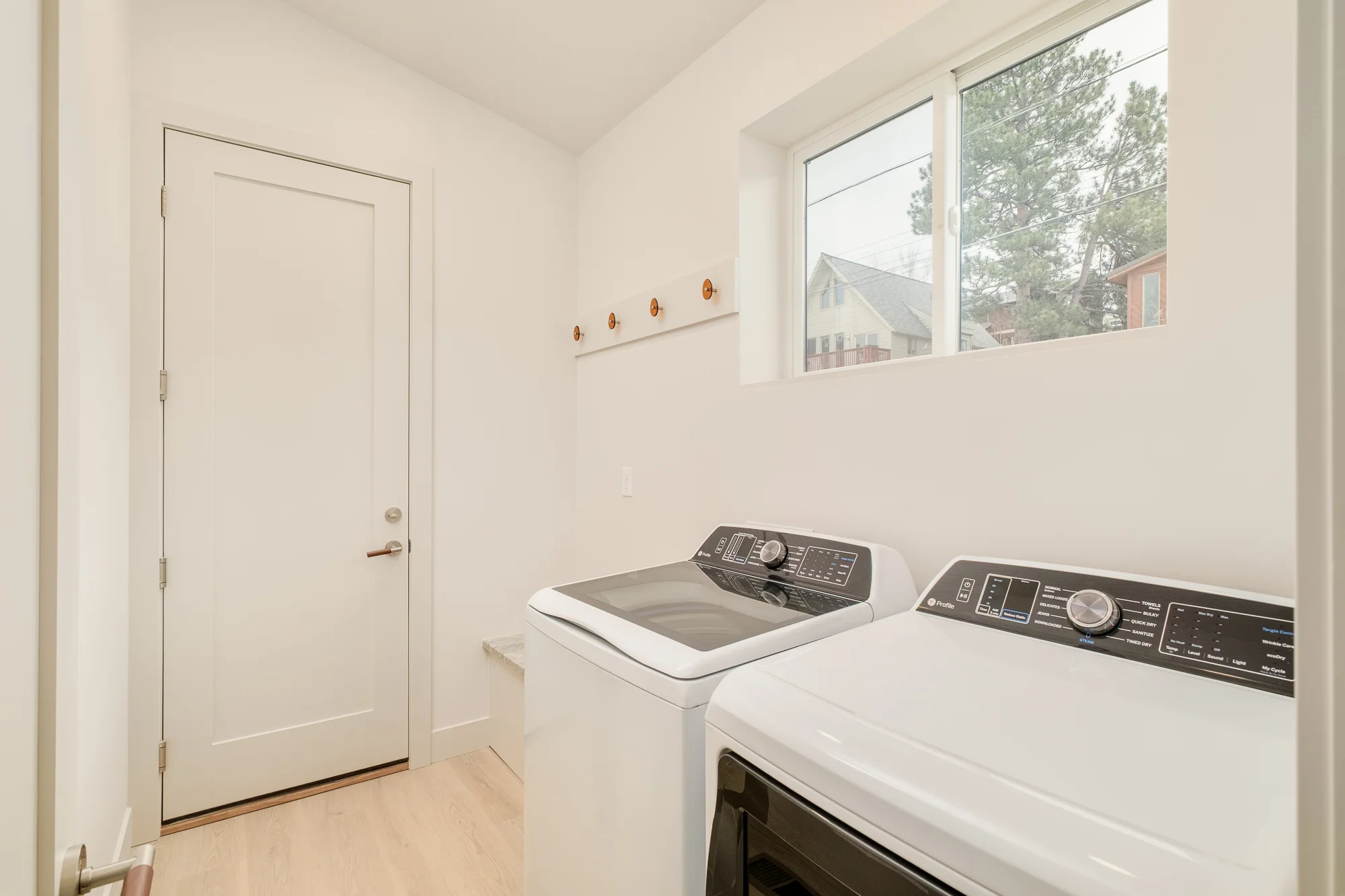 Laundry room with a window to the pines, a rail of amber glass hooks and a stone folding ledge