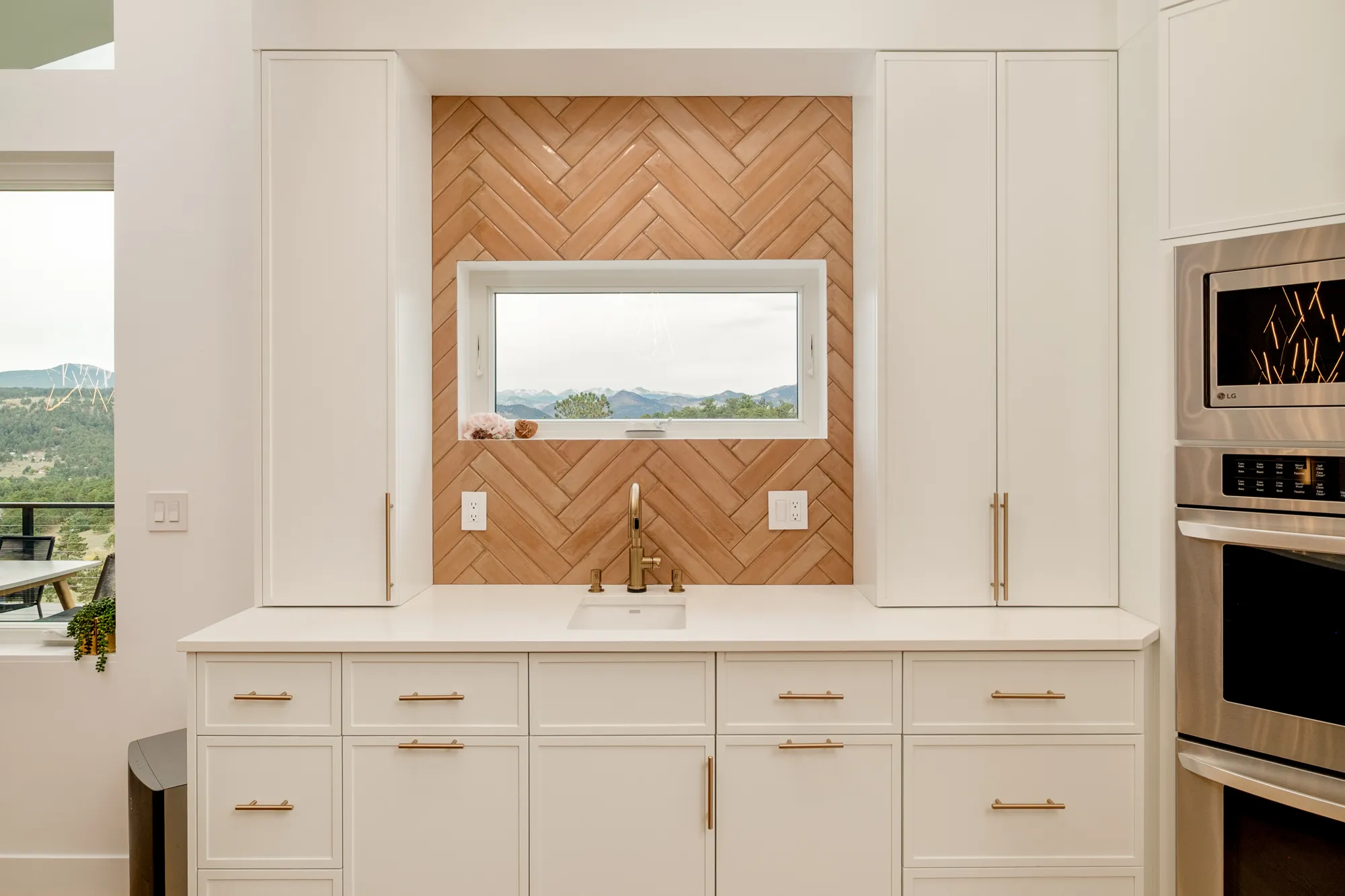 Herringbone wood backsplash framing a picture window above the kitchen sink