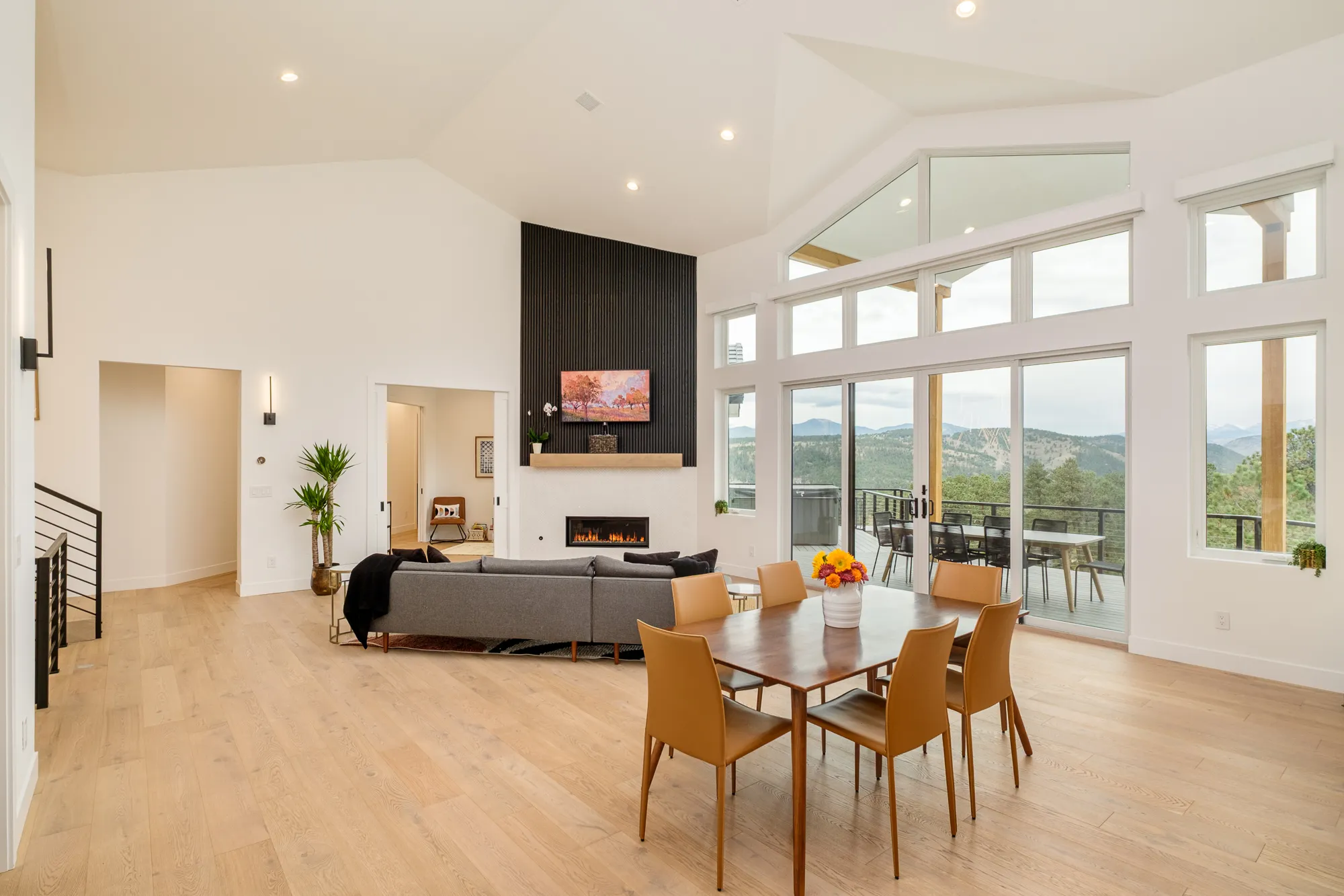 Dining table with cognac chairs beneath vaulted ceilings and a wall of windows