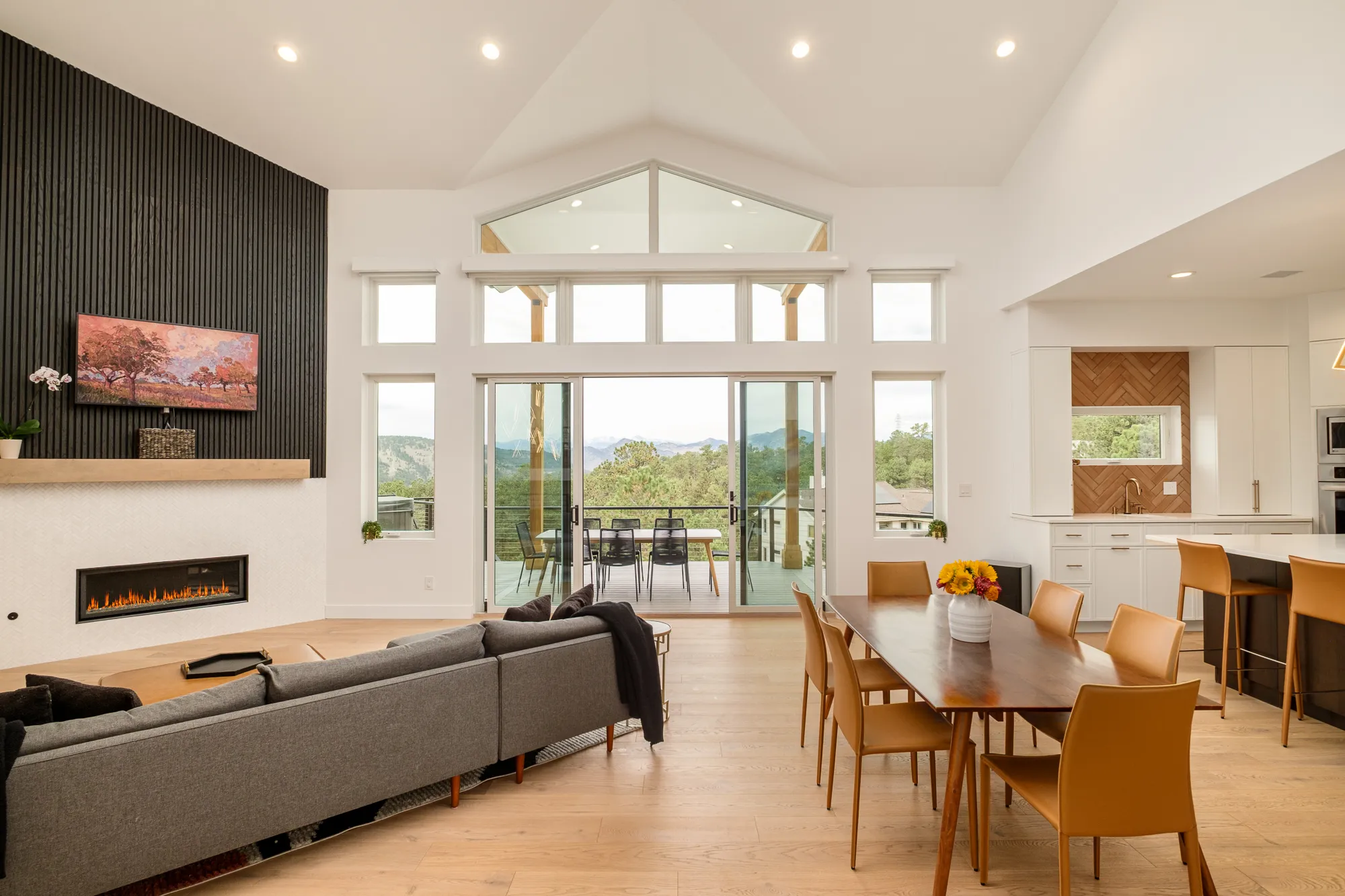Great room with a linear fireplace in a black-paneled wall and gabled windows