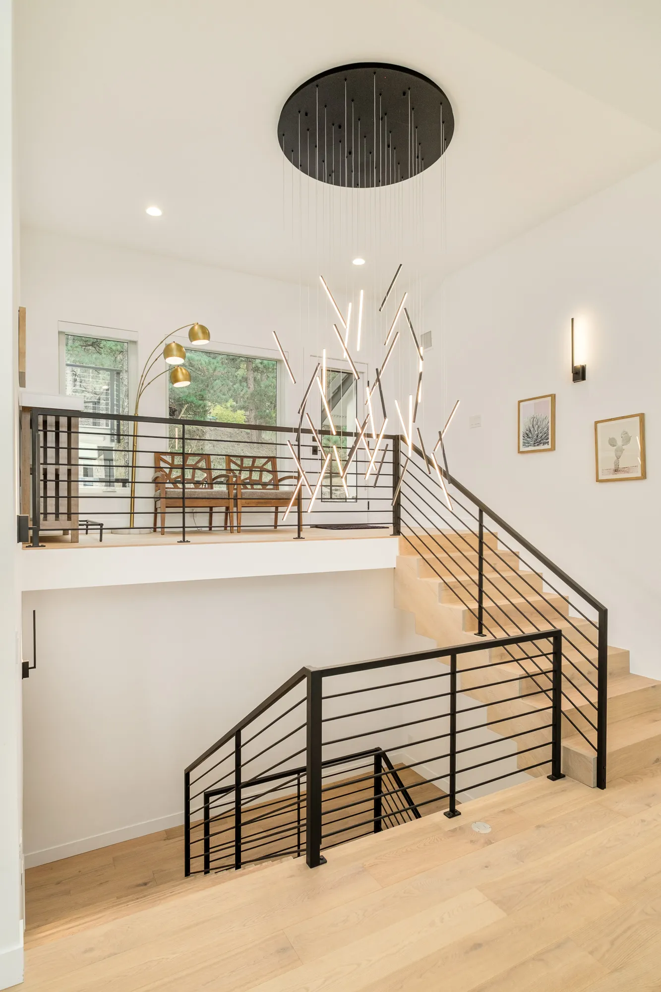 Open stair with black horizontal rails descending to the lower level