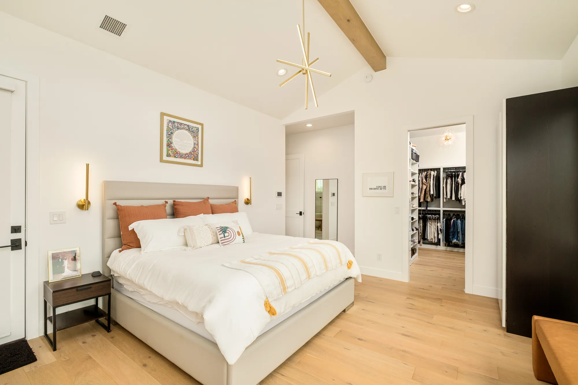 Primary bedroom with an upholstered bed and a view into the walk-in closet