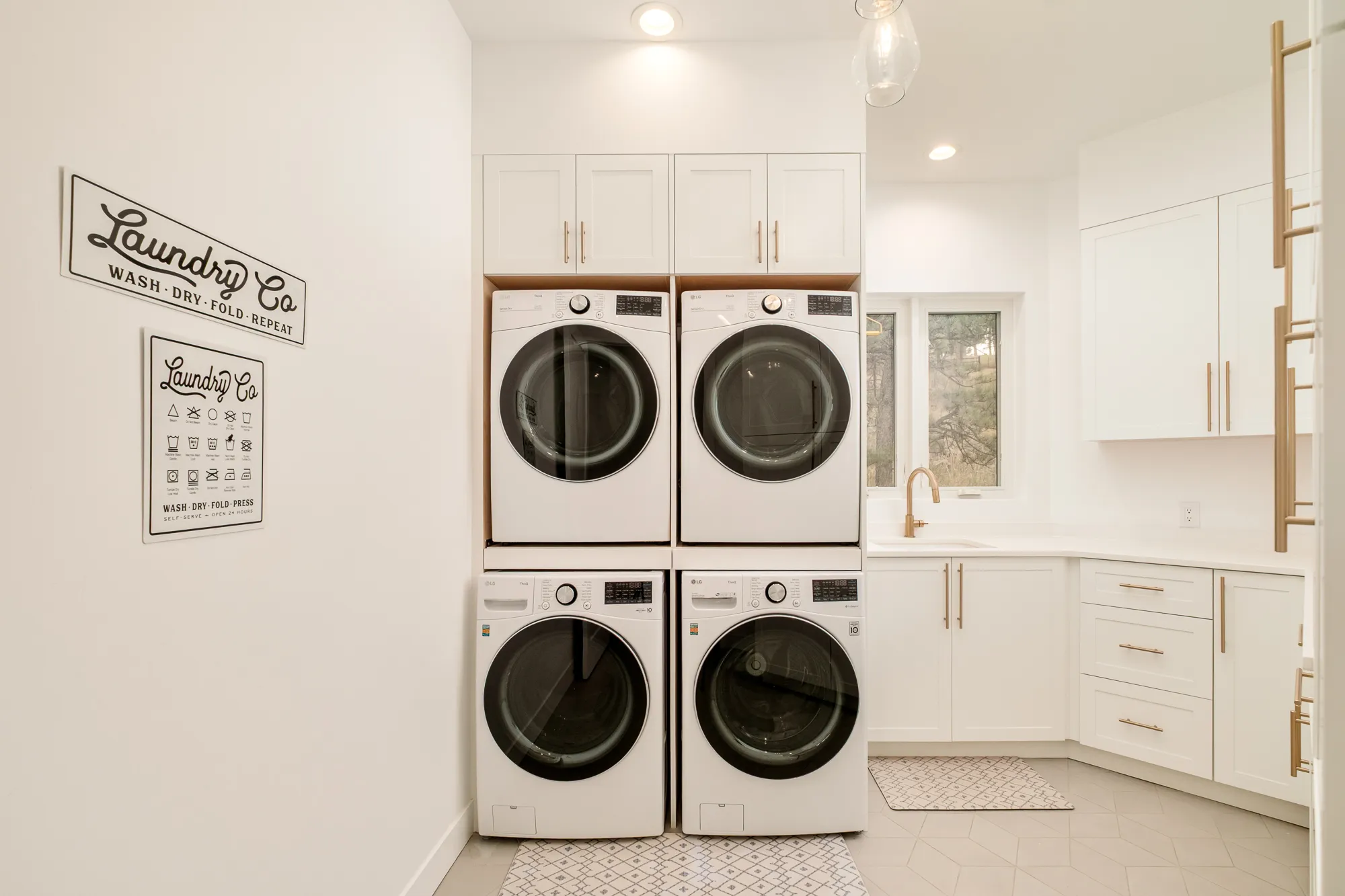 Laundry room with stacked washers and dryers and white cabinetry