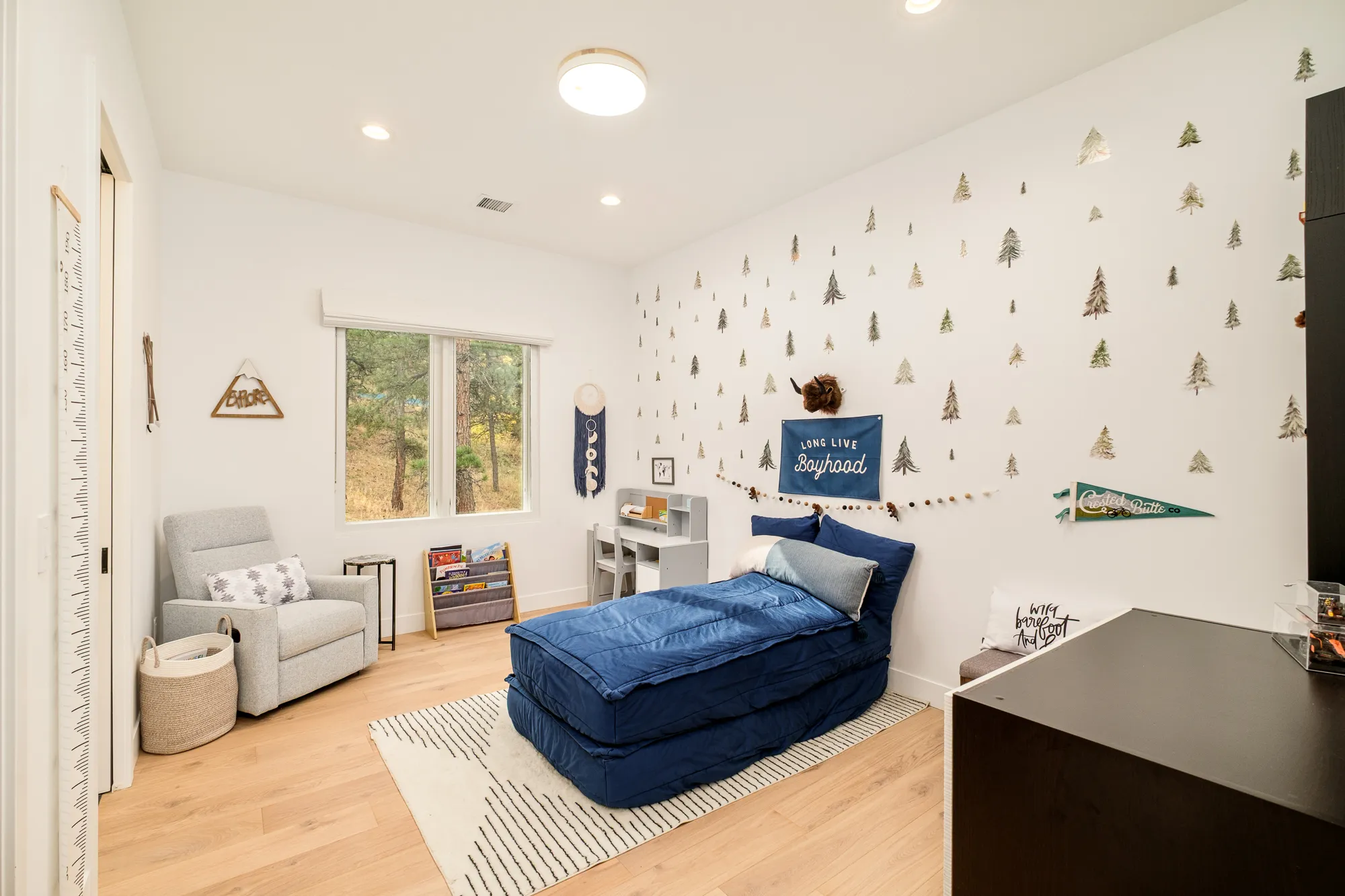 Child's bedroom with a navy daybed and tree-patterned wall decals