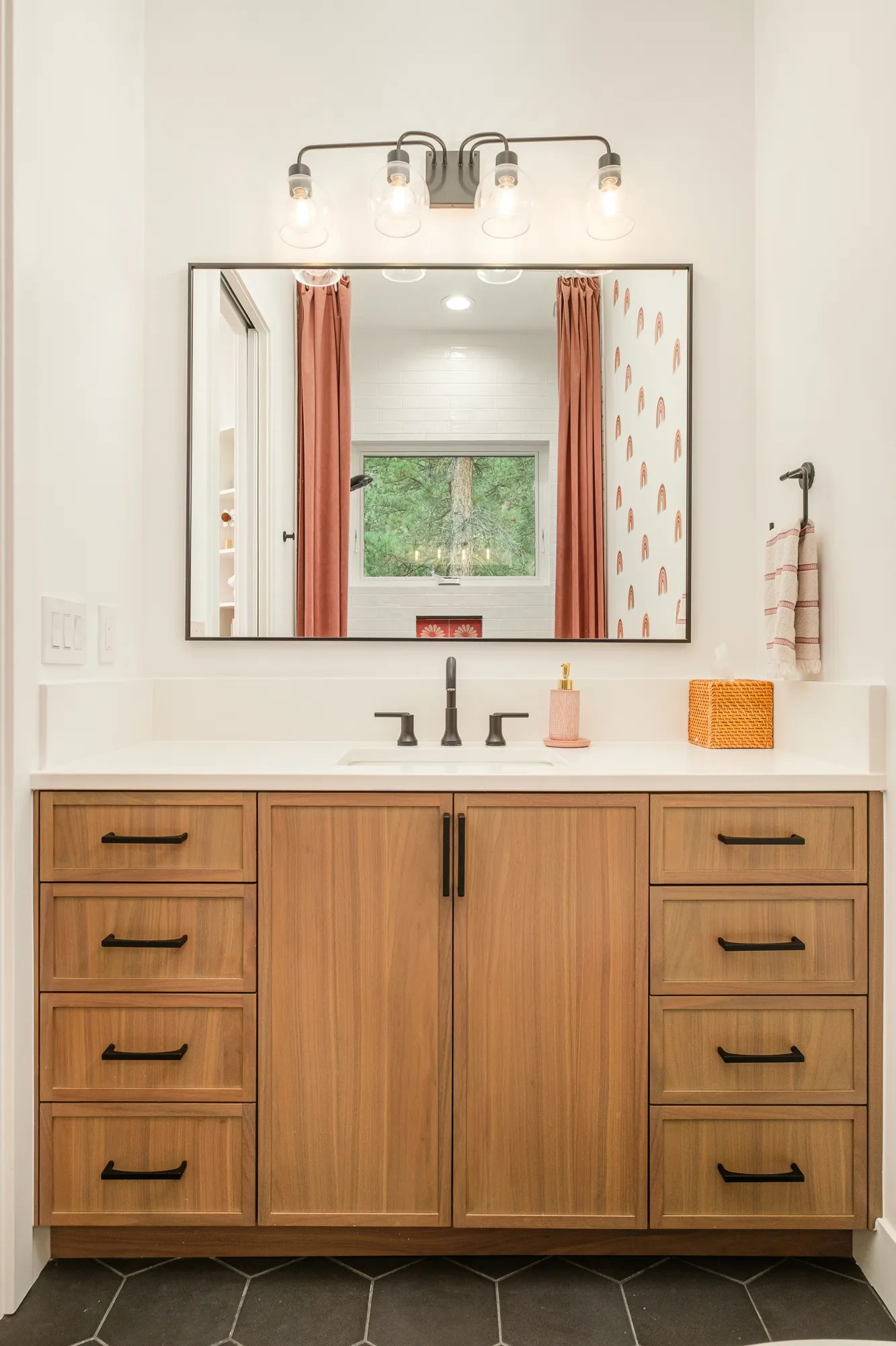 Bathroom vanity in warm wood with a black-framed mirror