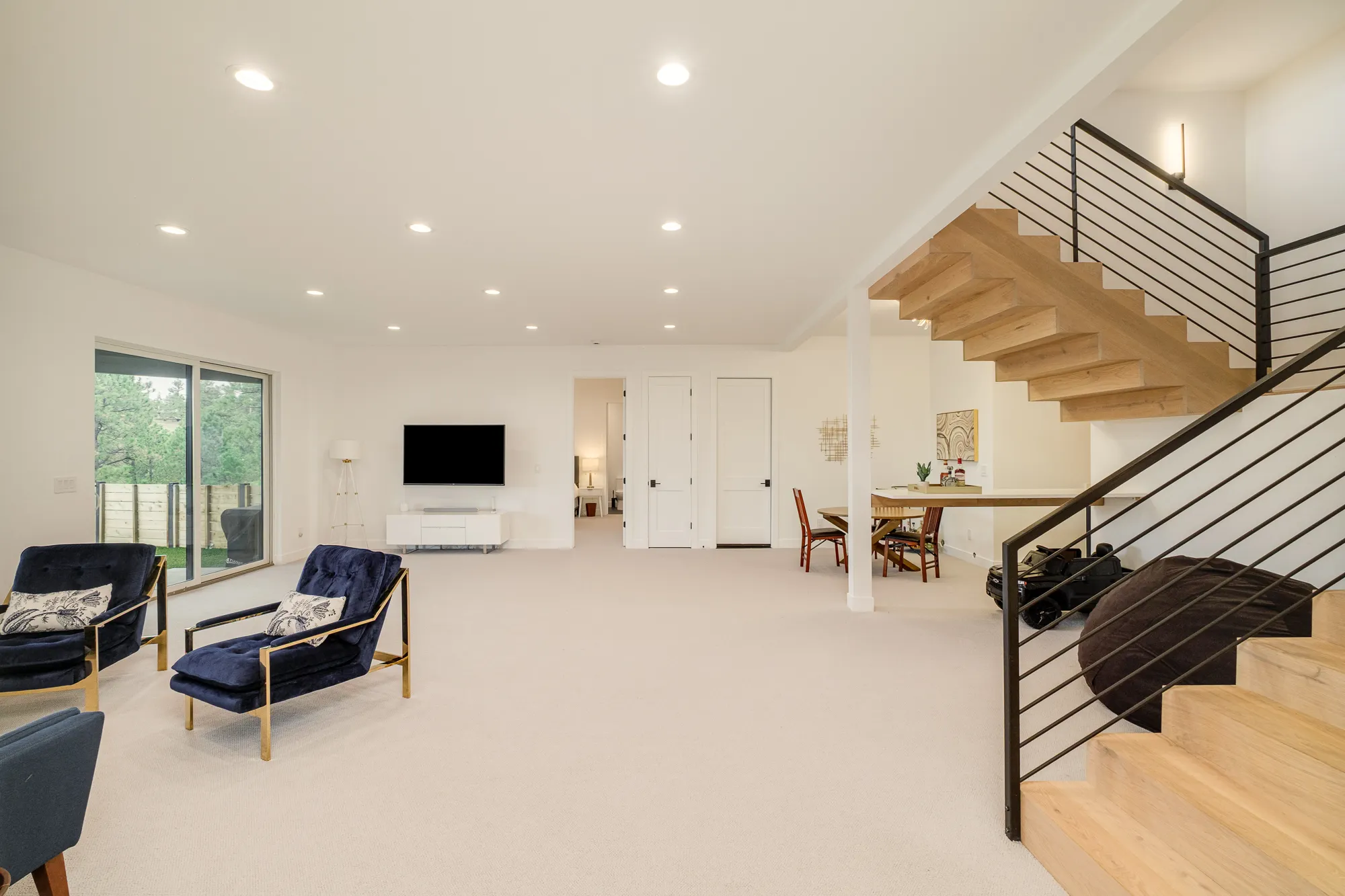 Lower-level lounge with navy chairs and a floating oak stair