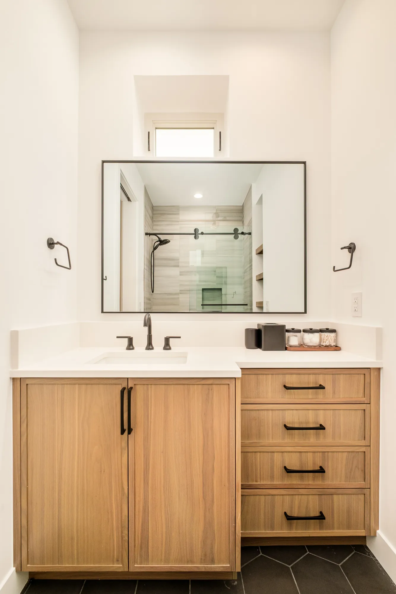 Guest bath vanity in wood with a black-framed mirror