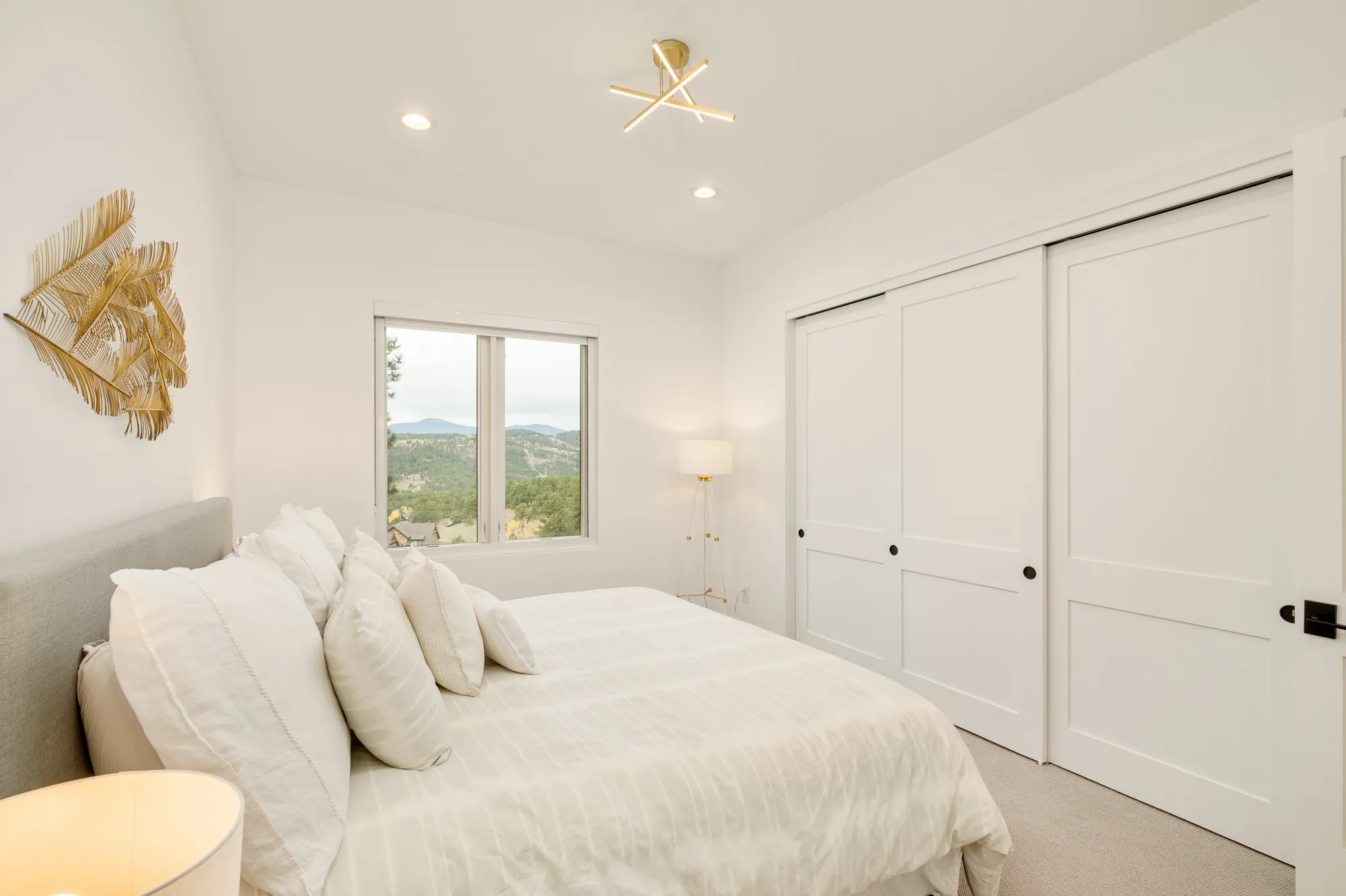 Bedroom with white sliding closet doors and a window to the trees
